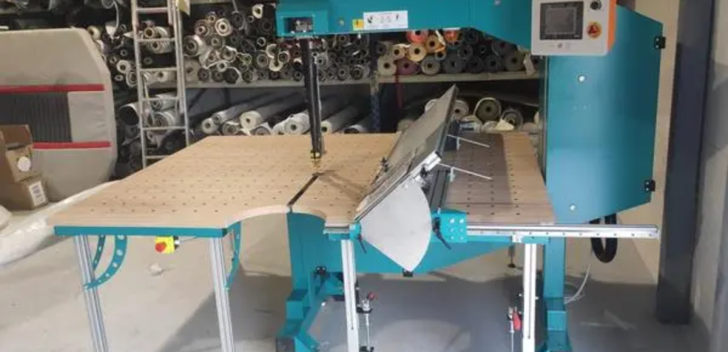 A band knife cutting machine precisely cutting fabric pieces with a continuous loop blade in a garment factory