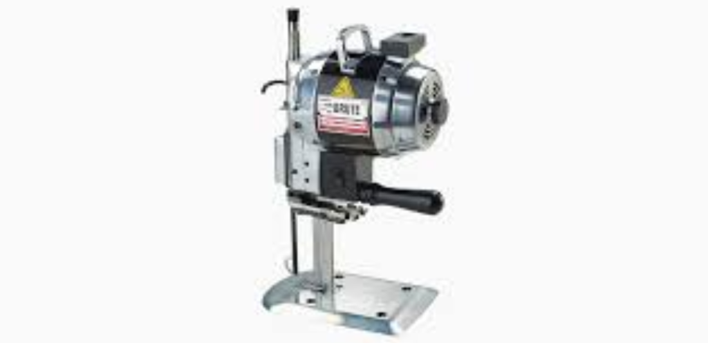 A straight knife fabric cutting machine cutting through multiple layers of fabric in a garment workshop